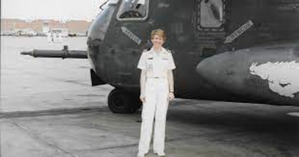 Woman in uniform smiling and posing for photo front of plane