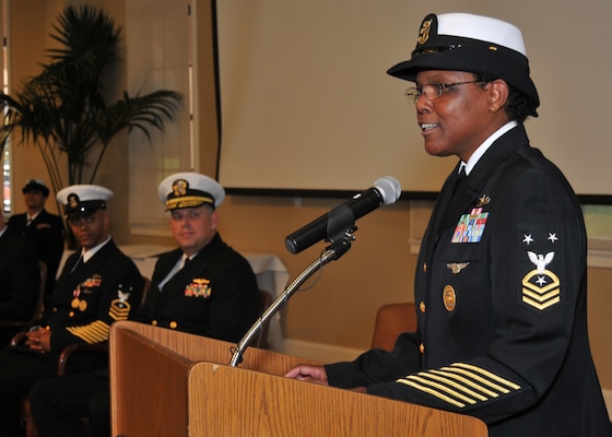 Octavia Harris in uniform speaking at podium with other sailors listening