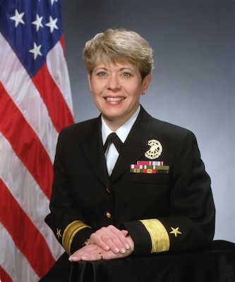 Smiling woman in uniform posing for official photo with USA flag in the background