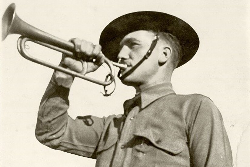 A soldier plays a bugle.