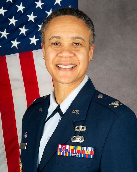 African American woman in blue uniform with American flag over right shoulder