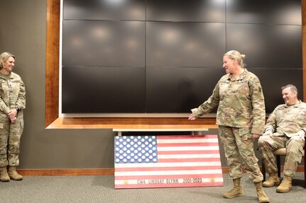 Chief Warrant Officer 4, Lindsay Glynn admires a gift presented to her by the staff of Joint Force Headquarters during her retirement ceremony Mar. 4, 2023.
