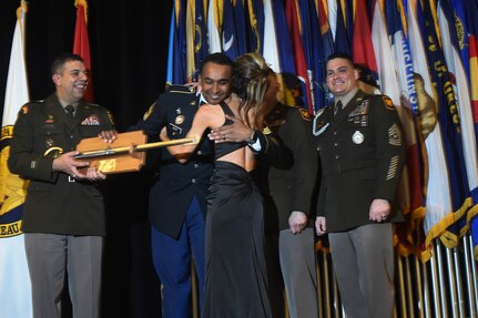 Master Sgt. Christopher Sehy, a recruiter with the Utah Army National Guard, embraces his wife, Crystal, as he receives the Army National Guard Recruiting and Retention Noncommissioned Officer of the Year award from Maj. Gen. John Andonie, left, deputy director of the Army National Guard, during the Director’s Strength Maintenance Awards and Conference in New Orleans, Louisiana, March 23, 2023. The conference brings together Army Guard recruiting team chiefs and the top Army Guard recruiters for training sessions and networking opportunities to tackle the challenges of recruiting.