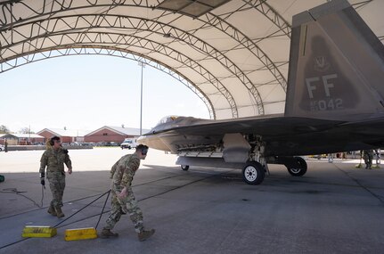 U.S. Airman 1st Class Cyede Khbais, 27th Fighter Generation Squadron crew chief, and Capt. Trent Amerson, 71st Fighter Generation Squadron commander, prepare to put chalks under one of the first two 71st Fighter Squadron F-22s to arrive at Joint Base Langley-Eustis, Virginia, Mar. 29, 2023.