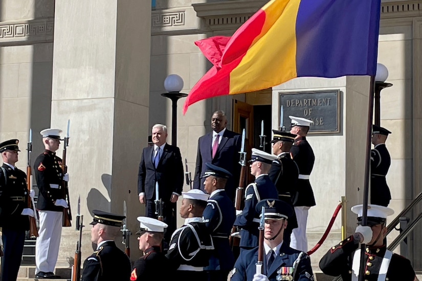 Two men stand at attention in the midst of an honor guard.