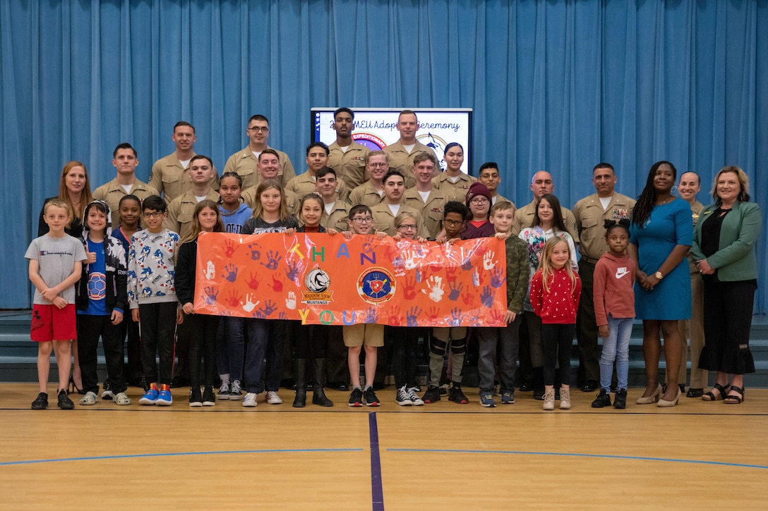 U.S. Marines with the 22nd Marine Expeditionary Unit (MEU) along with staff and students from Meadow View Elementary School, pose for a group photo commemorating the conclusion of an Adopt-A-School ceremony at Meadow View Elementary School in Jacksonville, North Carolina, March 29, 2023. The 22nd MEU and Meadow View Elementary School signed a Proclamation of Understanding, where Marines will volunteer to assist school staff while strengthening the relationship between the MEU and Meadow View Elementary school. (U.S. Marine Corps photo by Lance Cpl. Cameron Ross)