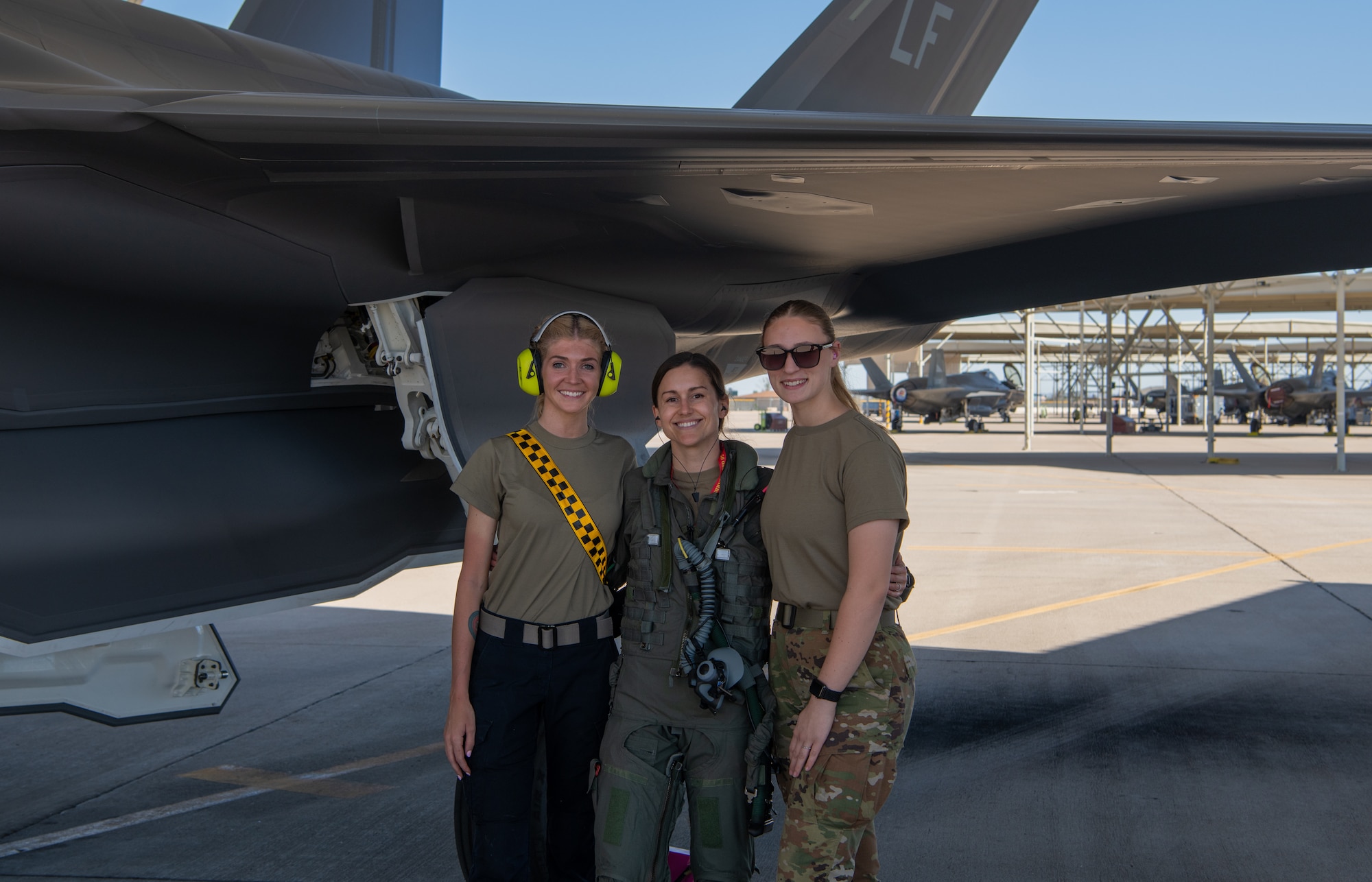 U.S. Air Force Staff Sgt. Paige Mitchell (left), 61st Fighter Squadron F-35 crew chief, U.S. Air Force Capt. Melanie Kluesner (middle), 62nd FS F-35 instructor pilot, and U.S. Air Force Airman Makenzie Milless, 62nd FS F-35 crew chief, pose for a photo at Luke Air Force Base, Arizona, Mar. 28, 2023.