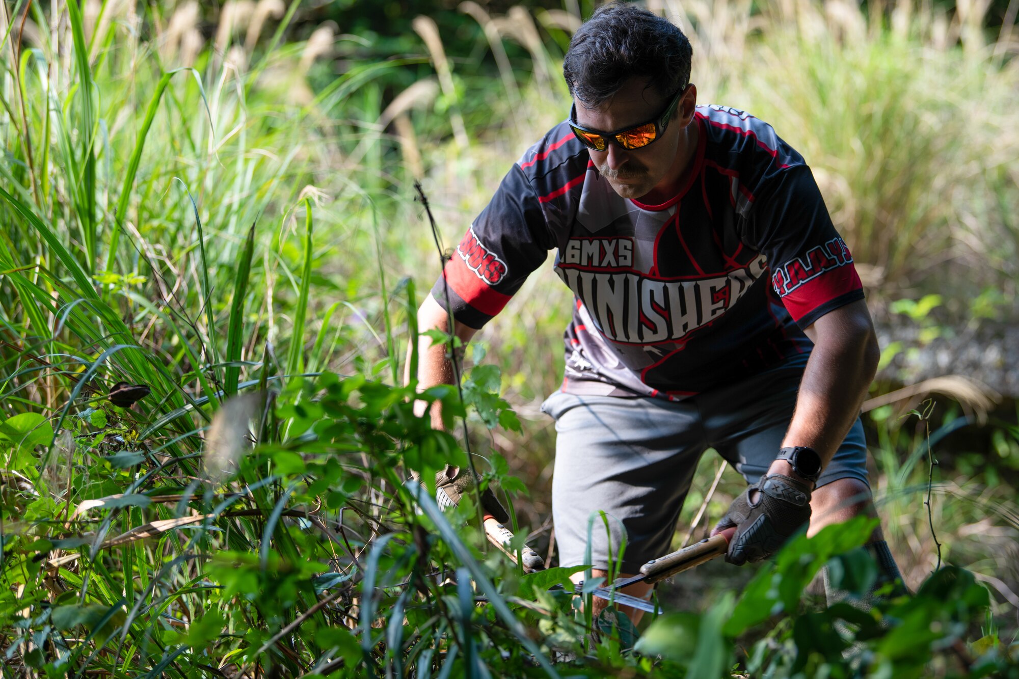 U.S. Air Force Staff Sgt. clearing a path of jungle vegetation towards a tomb.