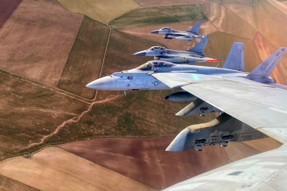 Planes fly side by side above farmland.