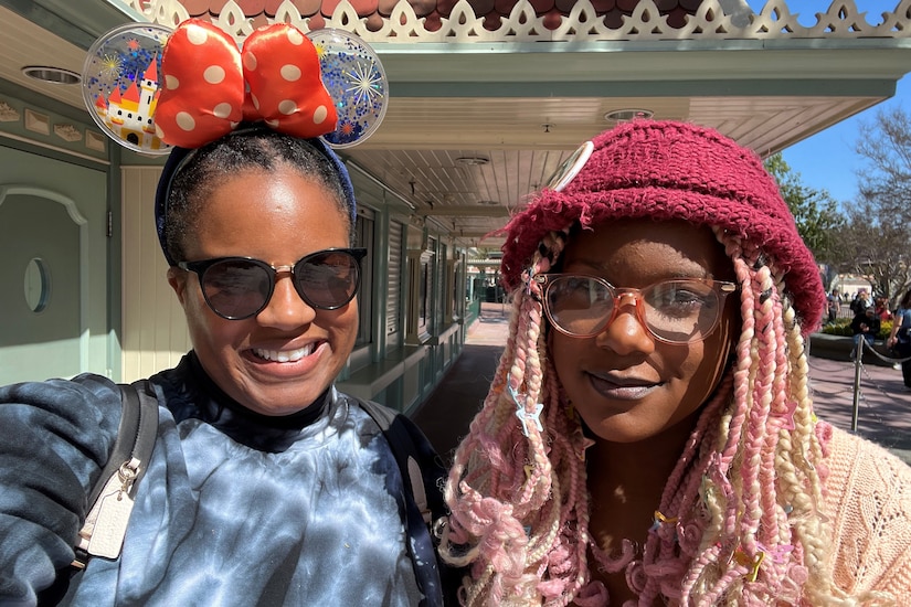 Two people pose for a photo, one wearing Minnie Mouse-type ears.
