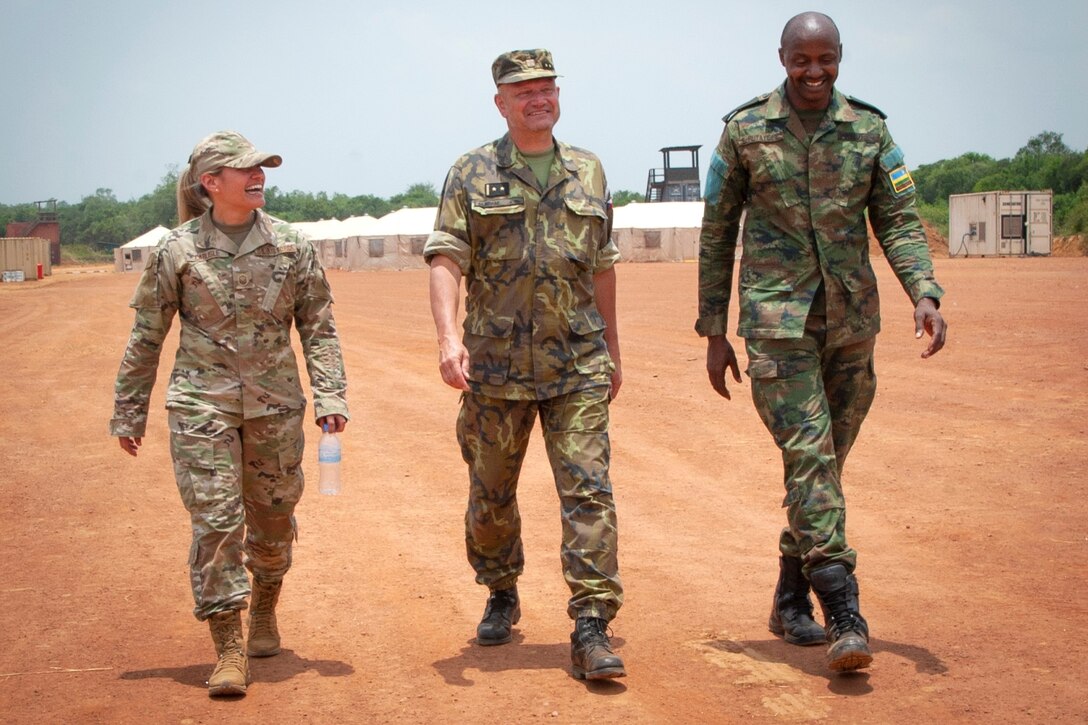 Nebraska Air National Guard Master Sgt. Jaclyn Carlisle, Lt. Col. Adam Miroslav of the Czech Republic, and Rwandan Defense Force Maj. B. Rutayisire exchange pleasantries while walking across the hospital training site at Gako, Rwanda, on March 16, 2022.