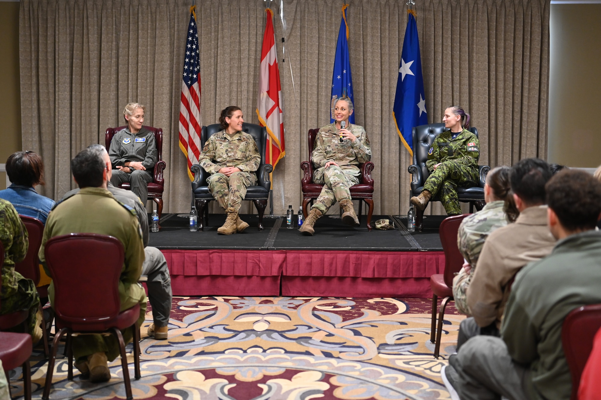 Four female Airmen sitting at panel in front of crowd