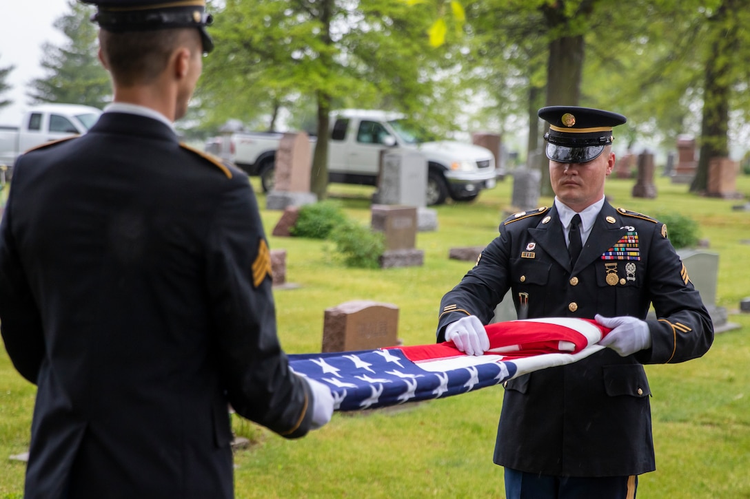 Nebraska National Guard Military Funeral Honors folds an American flag during a ceremony at the cemetery for a Veteran.