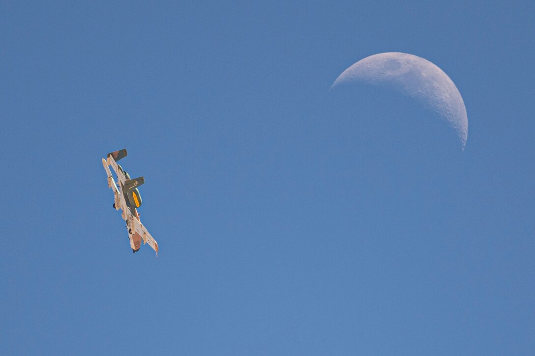 An aircraft flies on its side near the moon.