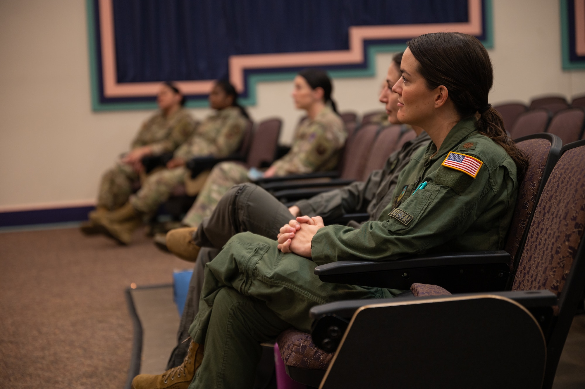 U.S. military members sit in theater seating while observing a womens history month panel