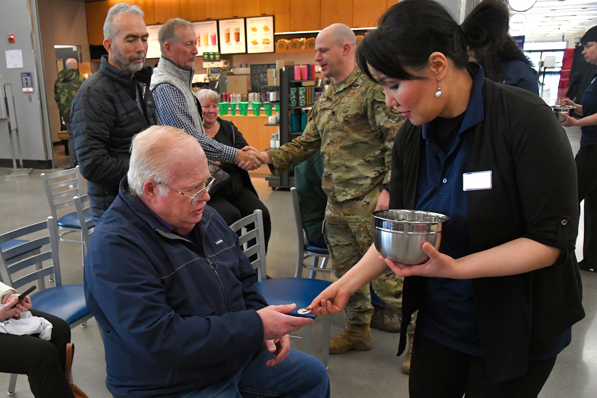 (Left to right) Bill Moran, a Vietnam veteran who served in the Air Force for 22 years, receives a commemorative coin from Chong Ahn, AAFES Mini mart manager, during a pinning ceremony March 29, 2023, at the AAFES Base Exchange at Hill Air Force Base, Utah. The ceremony was held to honor and remember Vietnam era veterans for National Vietnam Veterans Day. (U.S. Air Force photo by Todd Cromar)