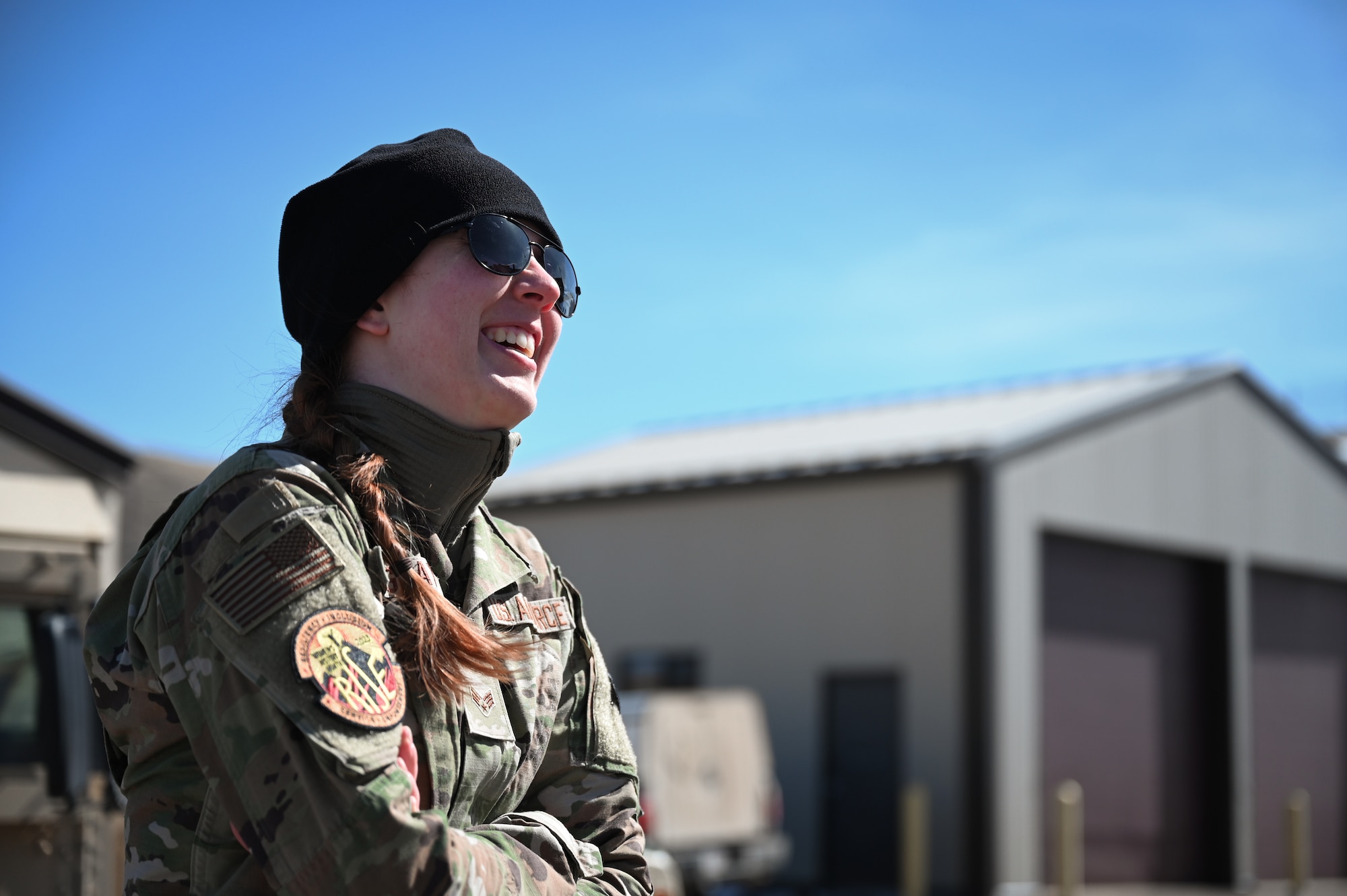 A woman in military uniform smiles towards the upper right hand corner of the image.