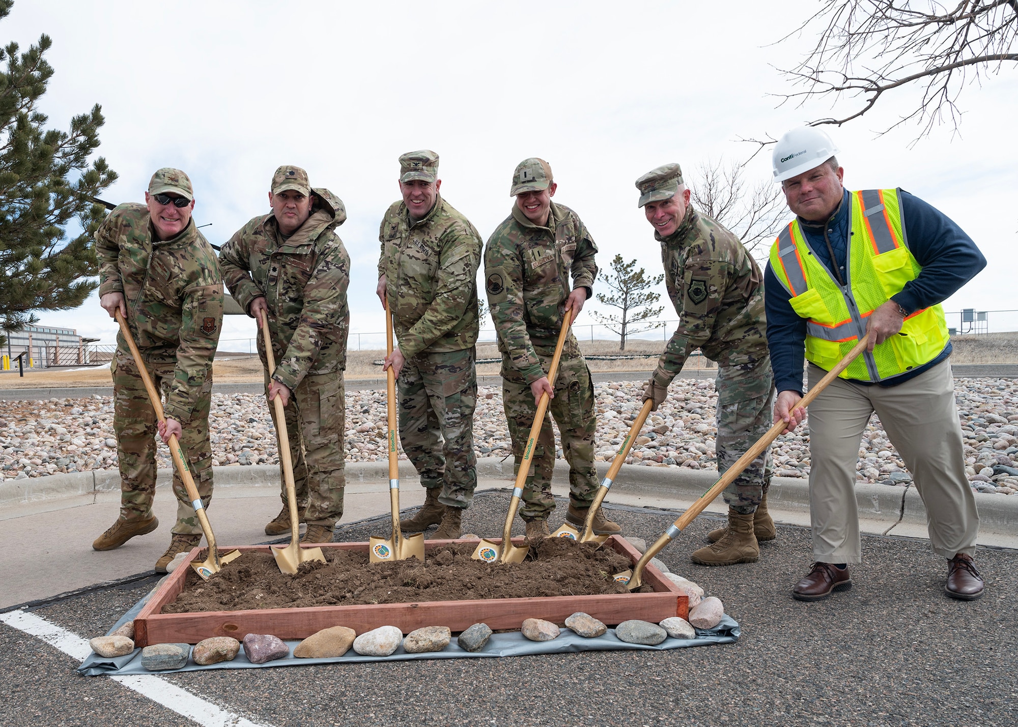 Six people dropping shovels into ceremonial earth