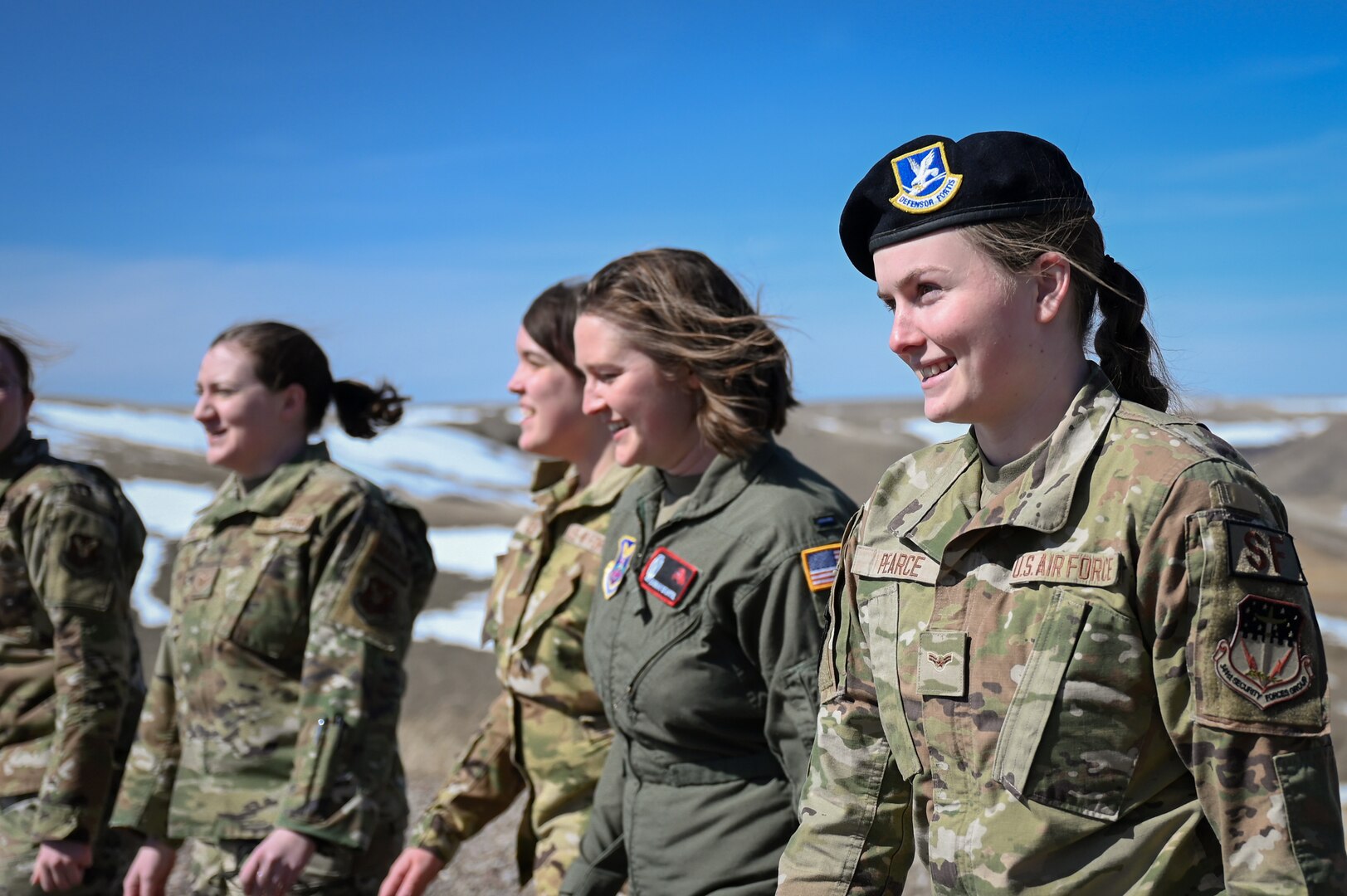A group of five women in military uniform walk alongside each other.