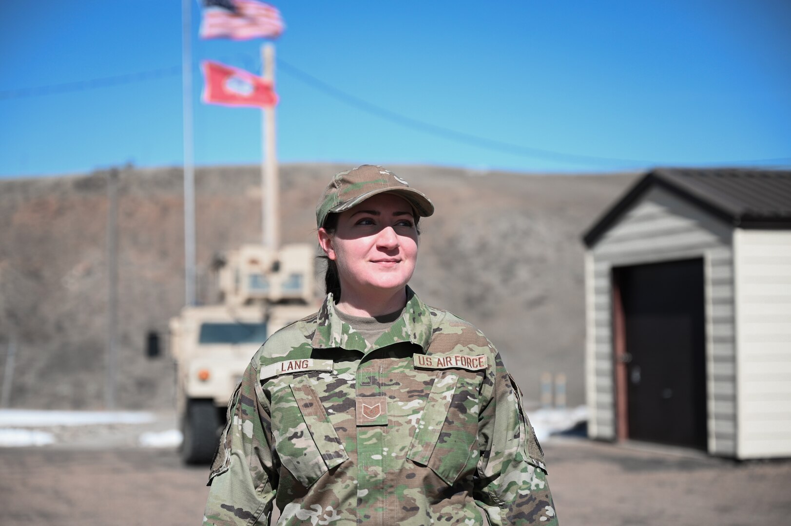 A woman in military uniform smiles towards the sun.