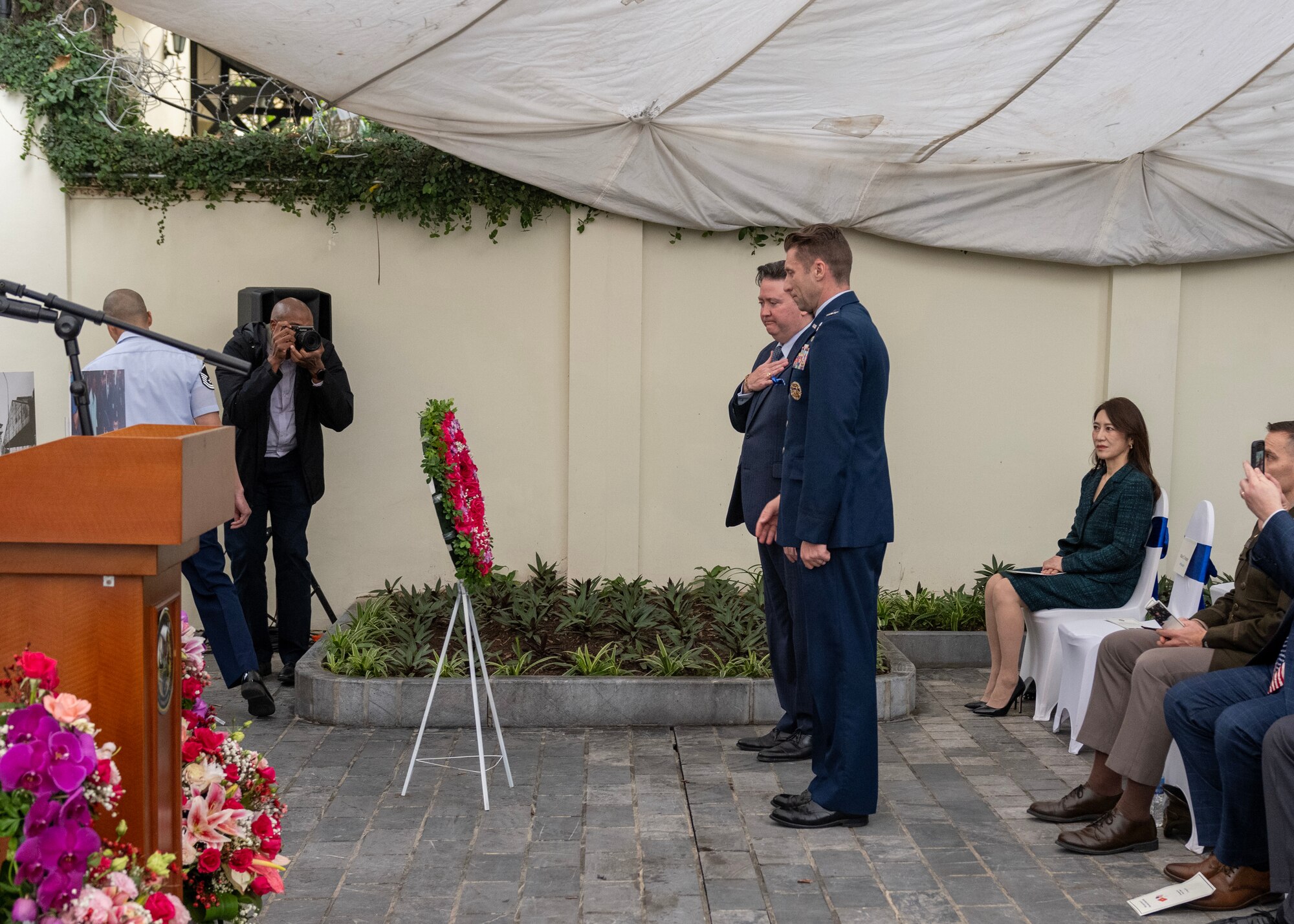 Officials stand in front of wreath during ceremony