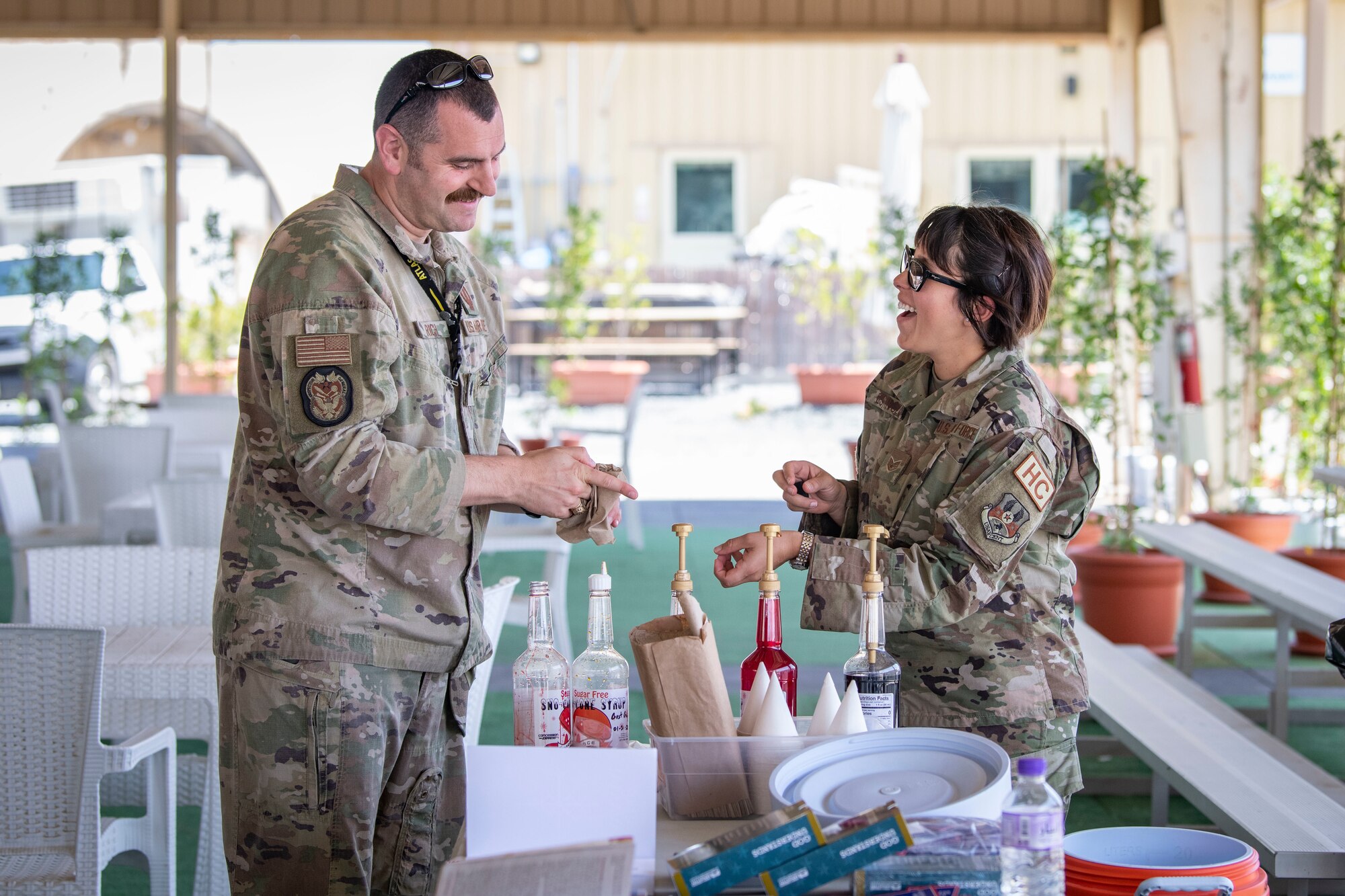 U.S. Air Force Lt. Col. Alex S. Rich, 386th Air Expeditionary Wing inspector general, left, and Staff Sgt. Elizabeth Espinoza Chaves, a 386th AEW chaplain assistant, work the snow cone station during a health fair at Ali Al Salem Air Base, Kuwait, April 27, 2023.