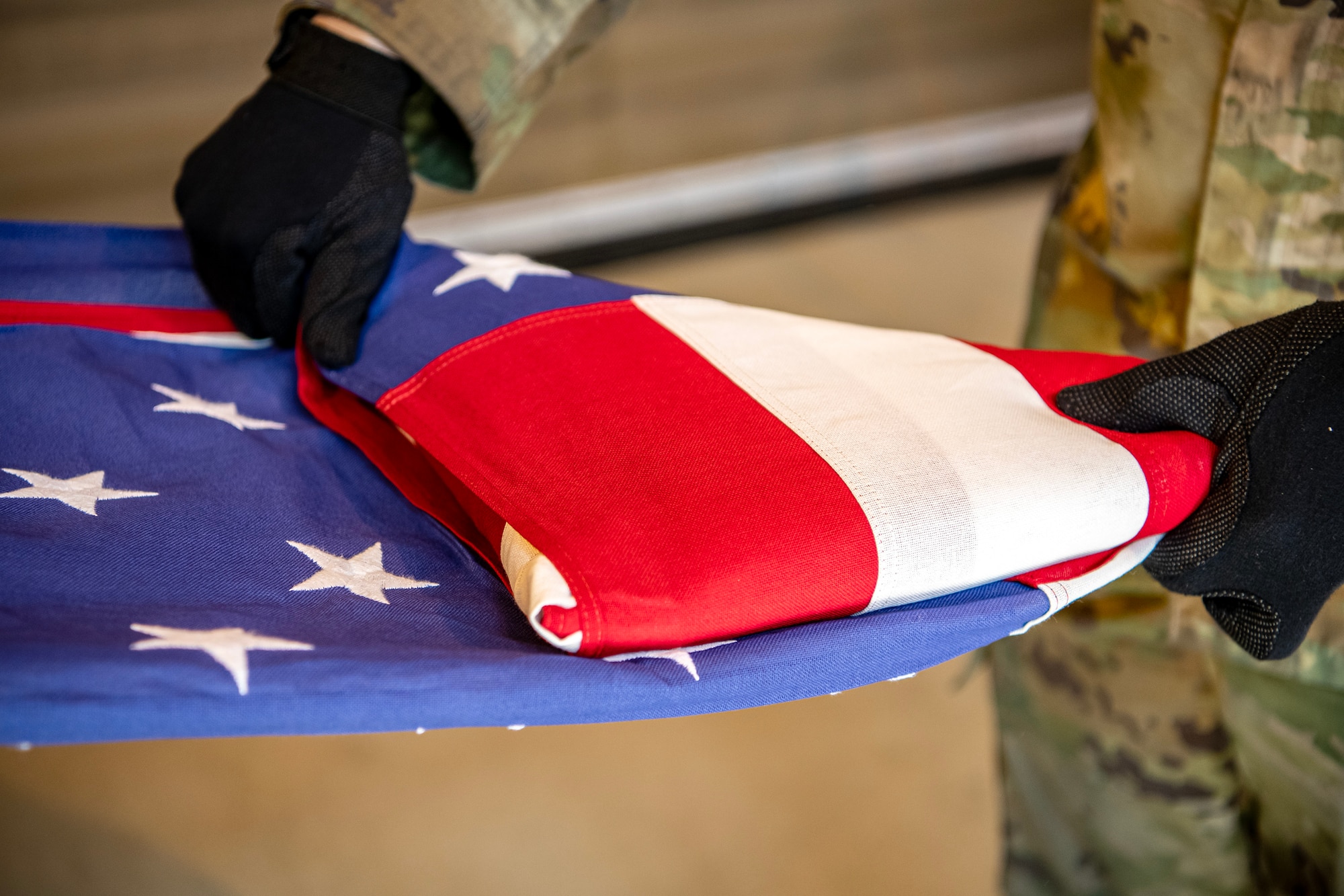 An Airman from the 423d Air Base Group Honor Guard folds a flag during training at RAF Alconbury, England, April 21, 2023. In order to become HG members, Airmen must complete rigorous initial training to ensure they are qualified to render military honors. (U.S. Air Force photo by Staff Sgt. Eugene Oliver)