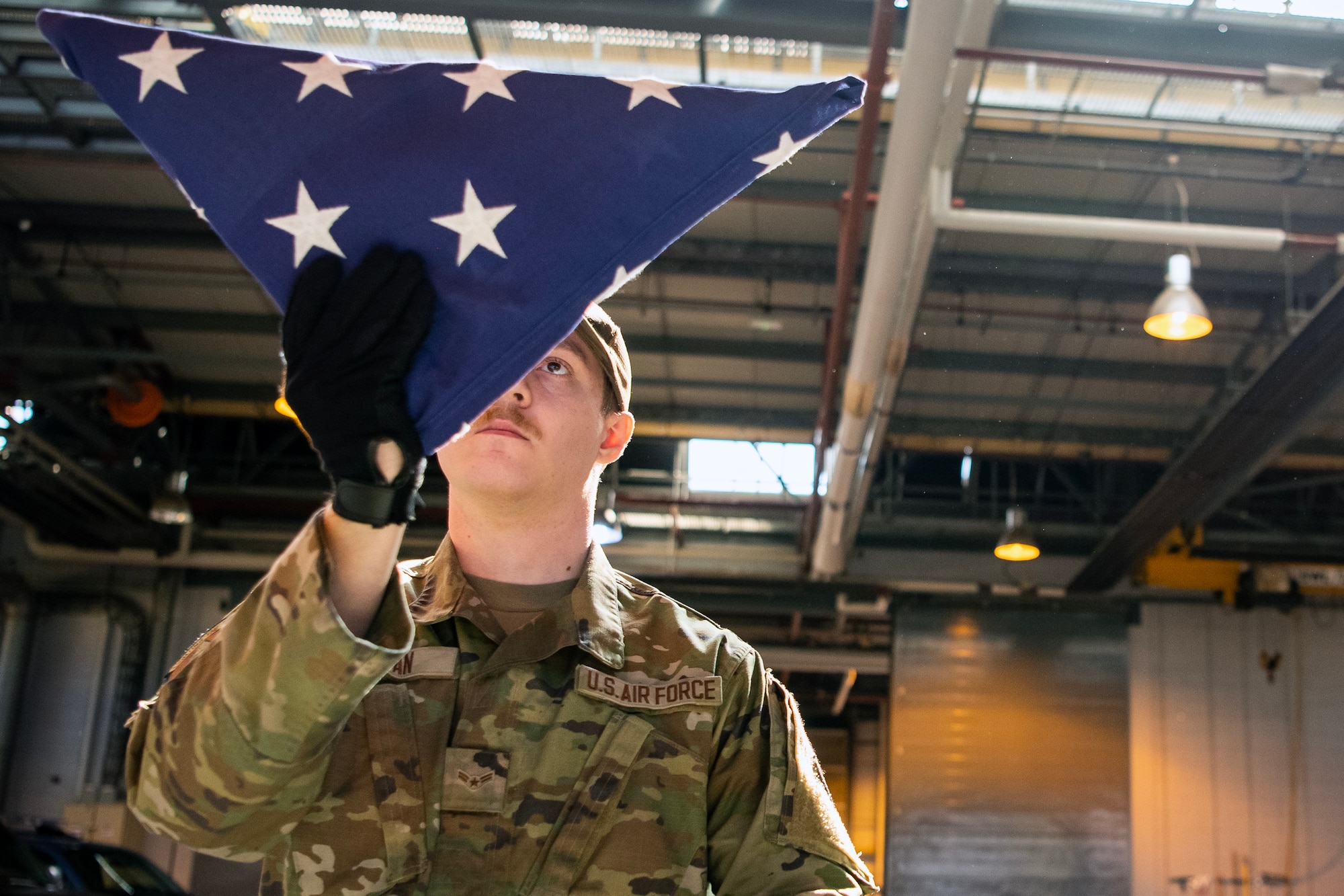 U.S. Air Force Airman 1st Class Spencer Eagan, 423d Air Base Group Honor Guard team member, dresses a flag at RAF Alconbury, England, April 21, 2023. In order to become HG members, Airmen must complete rigorous initial training to ensure they are qualified to render military honors. (U.S. Air Force photo by Staff Sgt. Eugene Oliver)