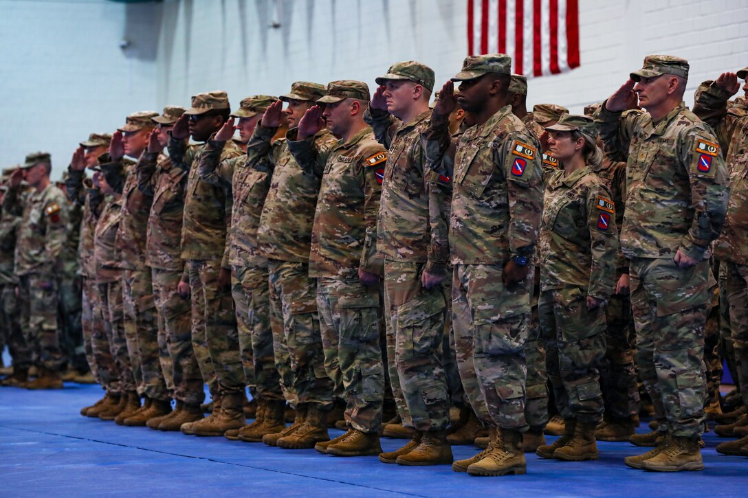 Soldiers stand at attention and salute.