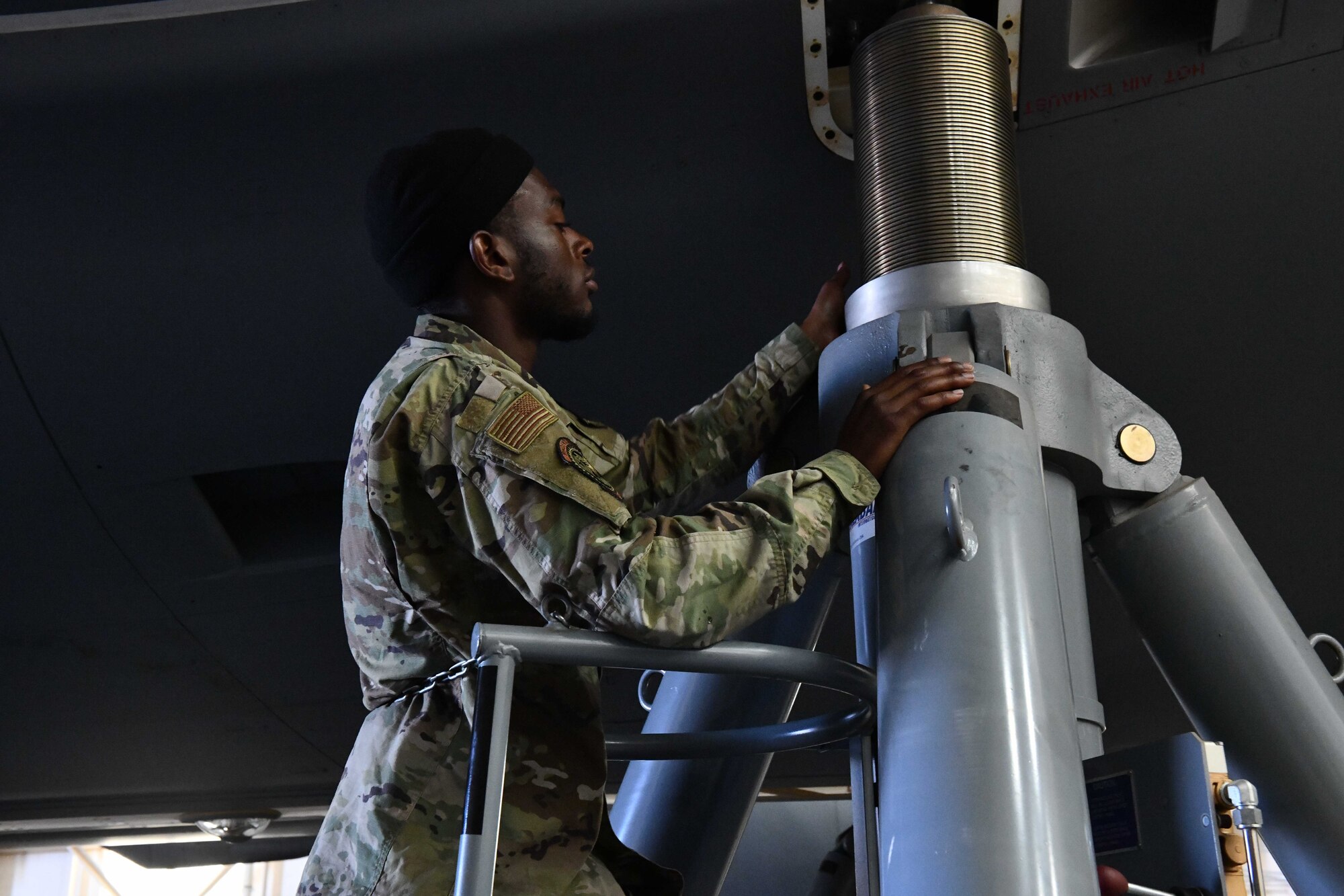 U.S. Air Force Airman 1st Class Nasir Savage, a 660th Aircraft Maintenance crew chief from Travis Air Force Base, Calif., tightens an aircraft jack ram lock at Altus Air Force Base, Oklahoma, April 18, 2023. The aircraft jack ram lock serves as a secondary locking mechanism for the jack, keeping the plane in place in case of a pressure drop. (U.S. Air Force photo by Airman 1st Class Miyah Gray)