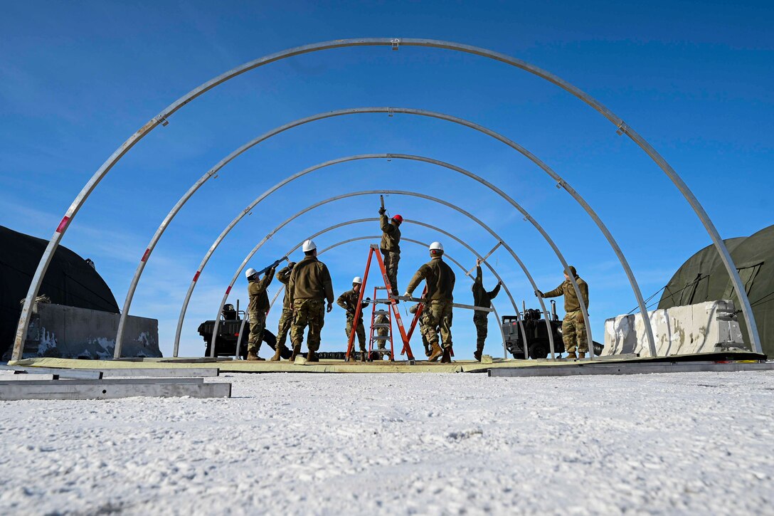 Airmen set up metal rods for a tent.