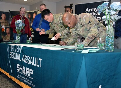 Members of U.S. Army Medical Logistics Command sign a banner in support of Sexual Assault Awareness and Prevention Month, or SAAPM, during an opening ceremony for the monthlong observance April 5, 2023, at Fort Detrick, Maryland.