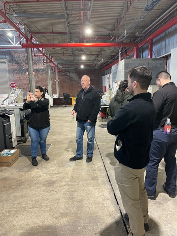 Group of males and female talking in a warehouse.