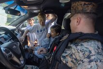 U.S. Marine Corps Lance Cpl. Gauge Funk, a military police officer, Marine Corps Base Hawaii Provost Marshall’s Office, allows a child to operate a speaker system in a patrol car during a Drug Education For Youth event (DEFY), MCBH, April 22, 2023. DEFY was established in 1993 by the Navy Drug Demand Reduction Task Force to teach children about substance abuse, bullying, and gang culture, and to provide them with alternative activities and positive life skills. (U.S. Marine Corps photo by Cpl. Chandler Stacy)