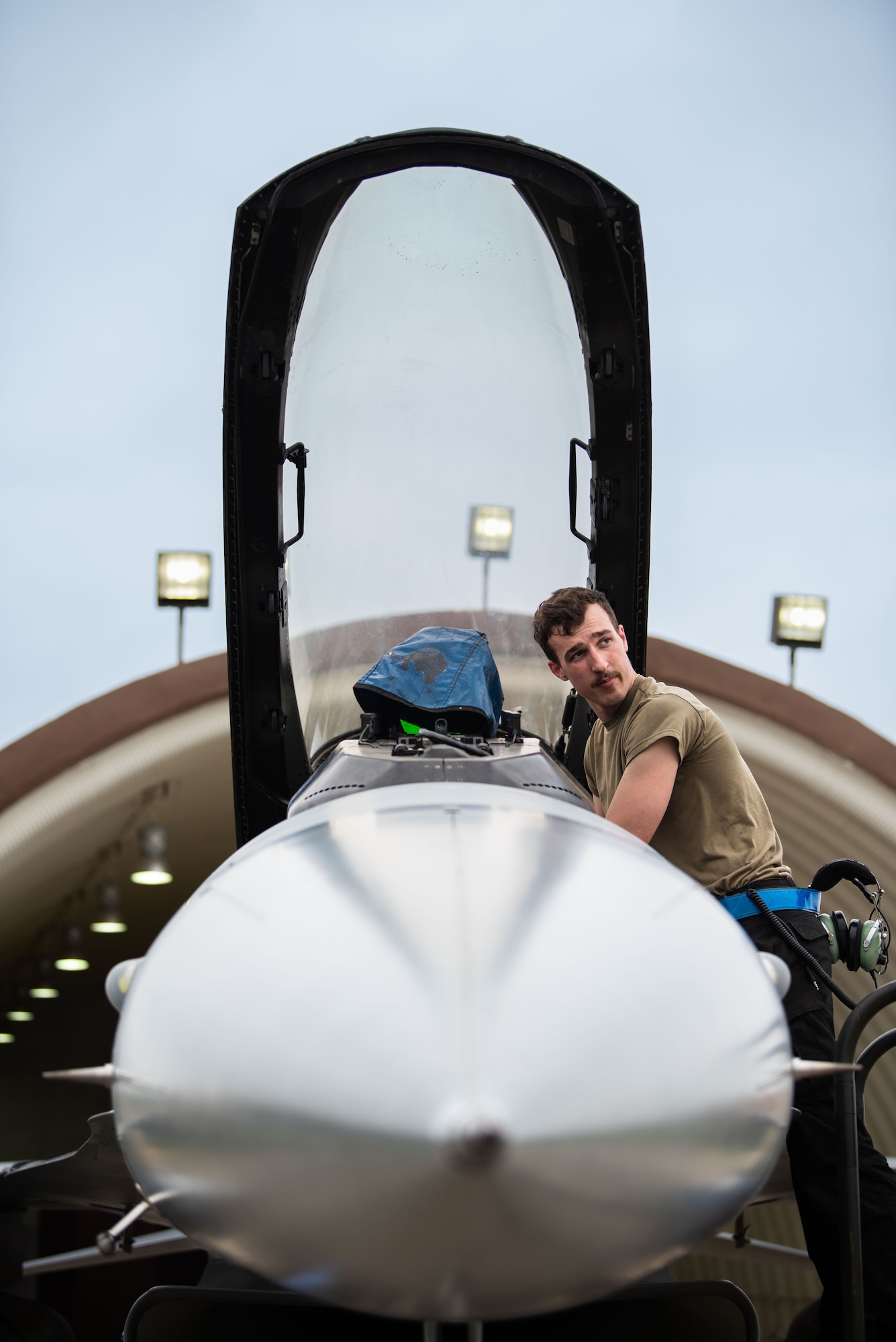 A maintainer looks in the distance while checking the cockpit of a jet