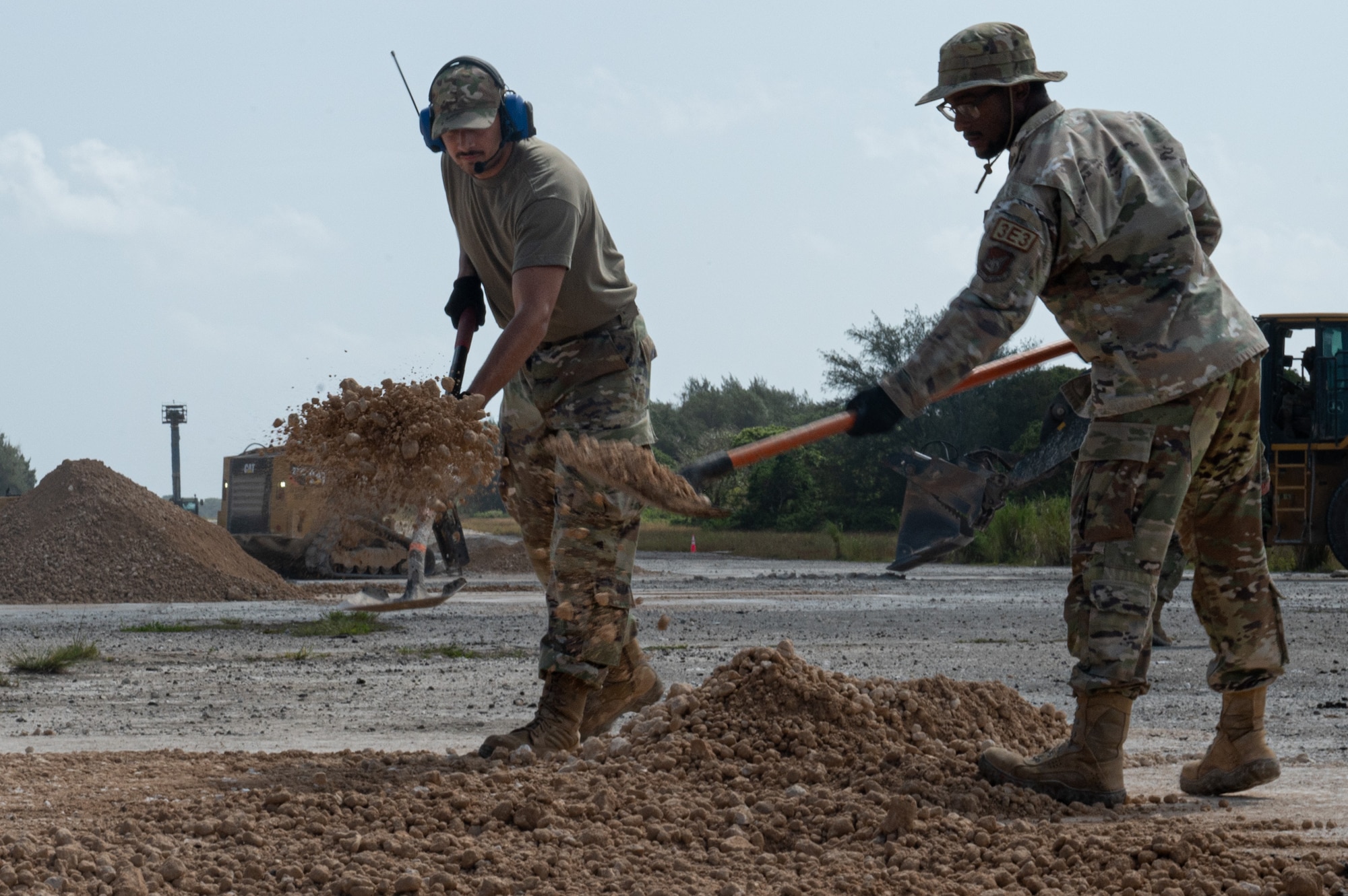 Airmen assigned to the 36th Civil Engineer Squadron shovel debris during an expedient and expeditionary airfield damage repair demonstration hosted by Headquarters Pacific Air Forces Civil Engineer Division at the Pacific Regional Training Center-Andersen, Guam, April 20, 2023. Sixteen Airmen from the 36th CES were provided two days of vehicle and material familiarization from the 554th Rapid Engineer Deployable Heavy Operational Repair Squadron Engineers and the Air Force Civil Engineer Center to complete airfield damage repair using the smaller packages of Airmen and equipment, called E-ADR. They used their familiarization to validate the E-ADR concept, in support of a Pacific Air Forces agile combat employment initiative, repairing 10 craters with a lighter and leaner vehicle and equipment kit that weighs a fraction of a standard Rapid Airfield Damage Recovery package. (U.S. Air Force photo by Staff Sgt. Suzie Plotnikov)