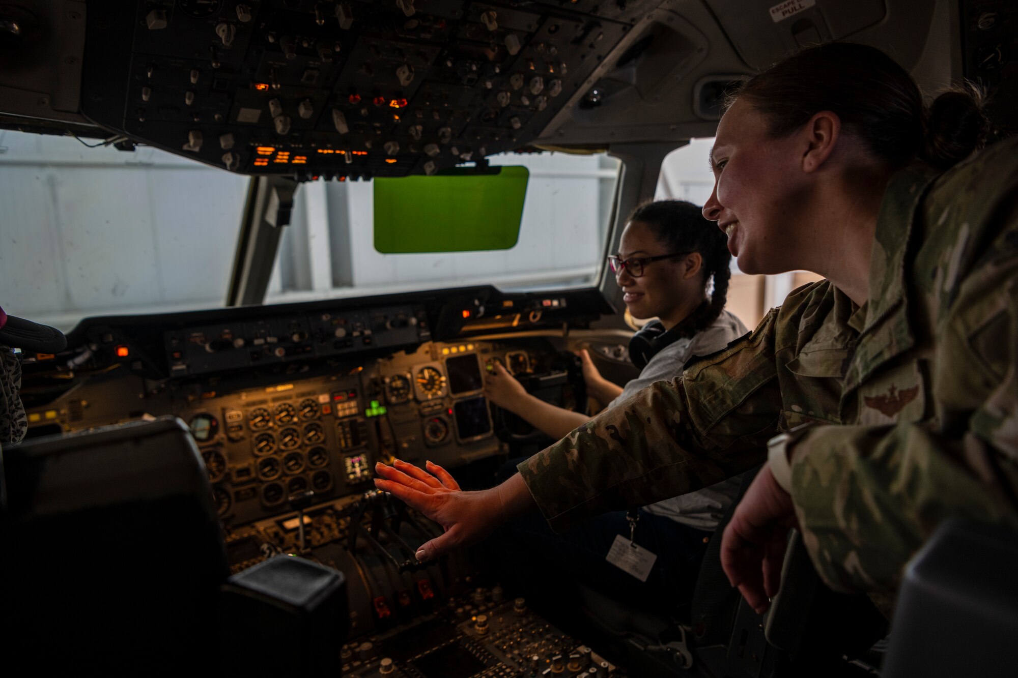 A woman shows a girl controls inside an airplane.