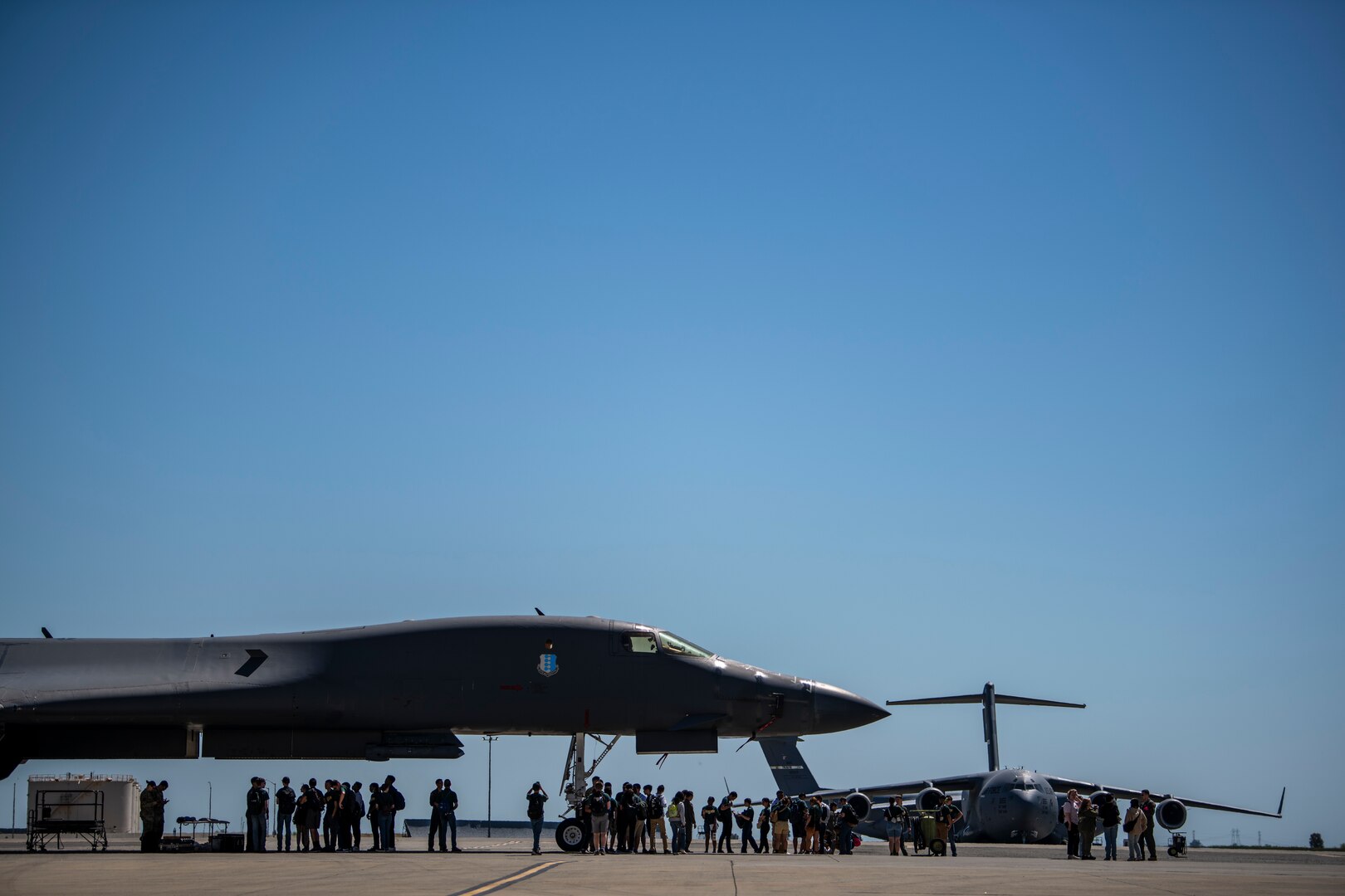 People stand around a military aircraft.