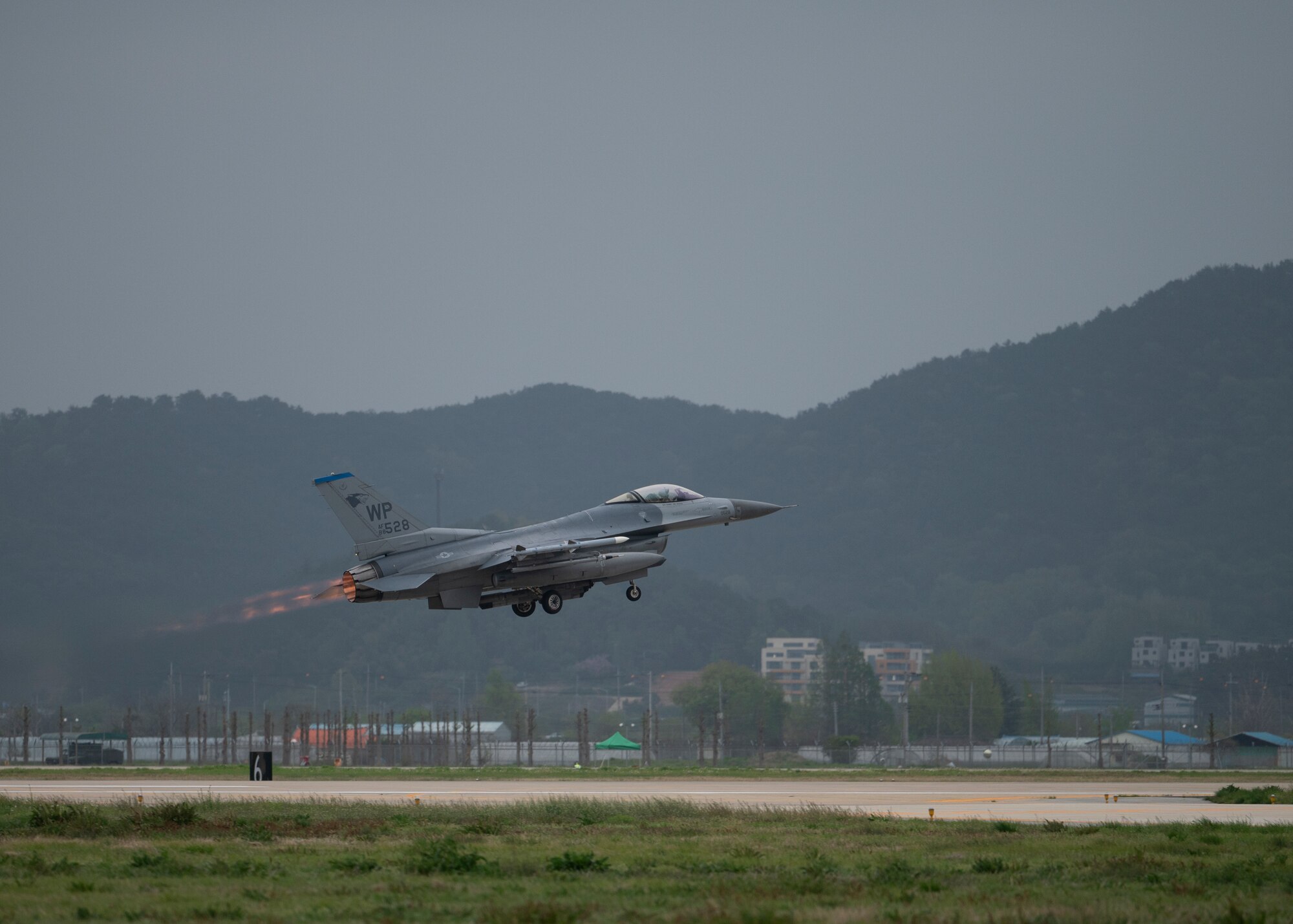 A jet takes off with afterburn visible