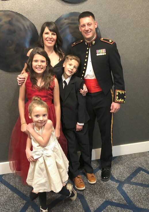  Man in uniform poses for a family photo with his wife, two daughters, and son