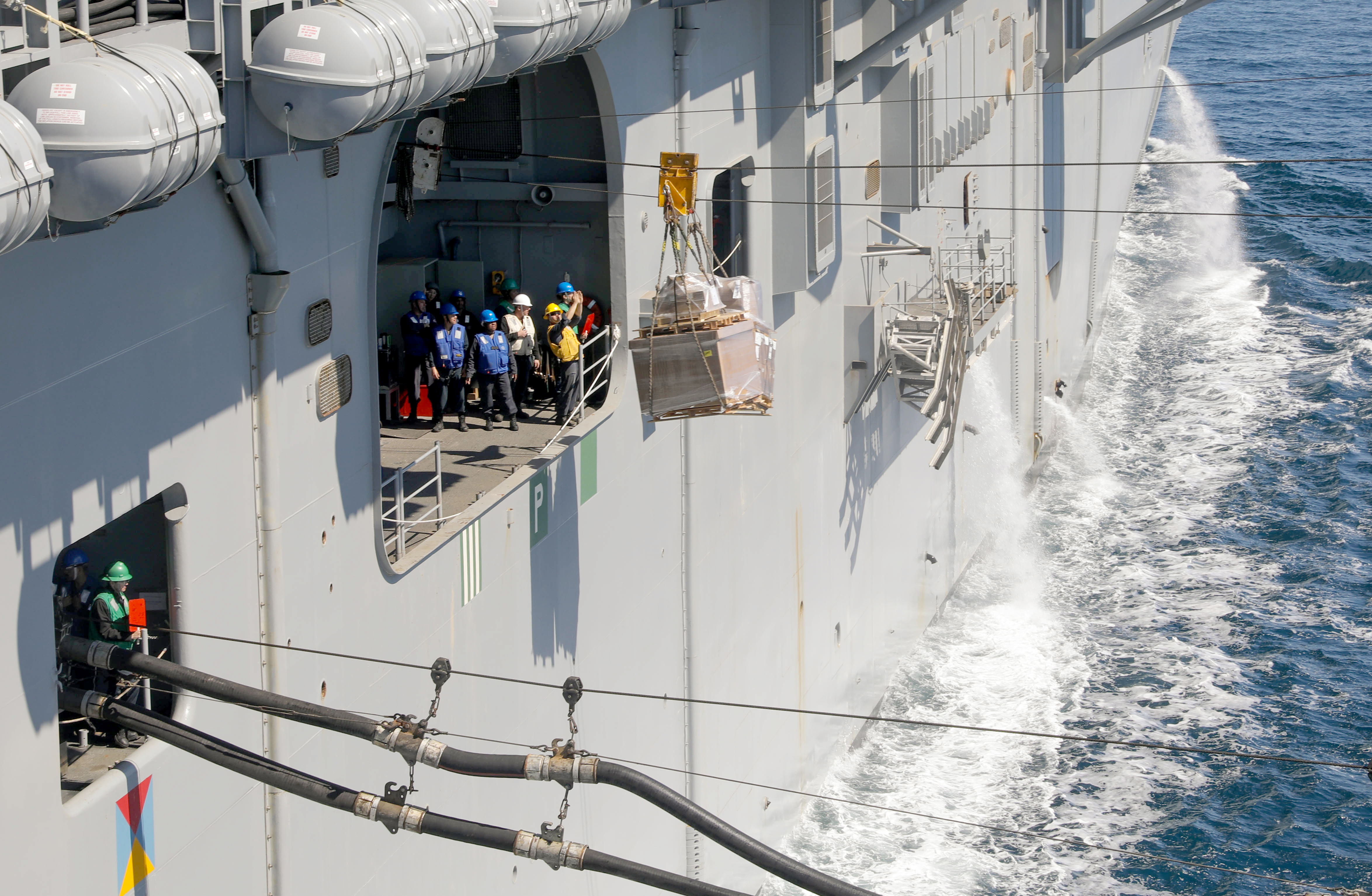 Sailors receive a pallet aboard USS Wasp (LHD 1) during a replenishment with USNS Leroy Grumman (T-AO 195).