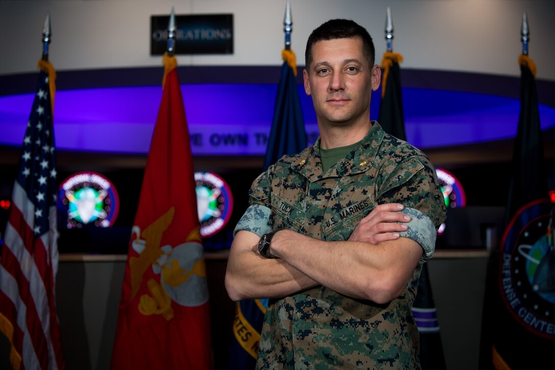 Marine in uniform stands with his arms crossed