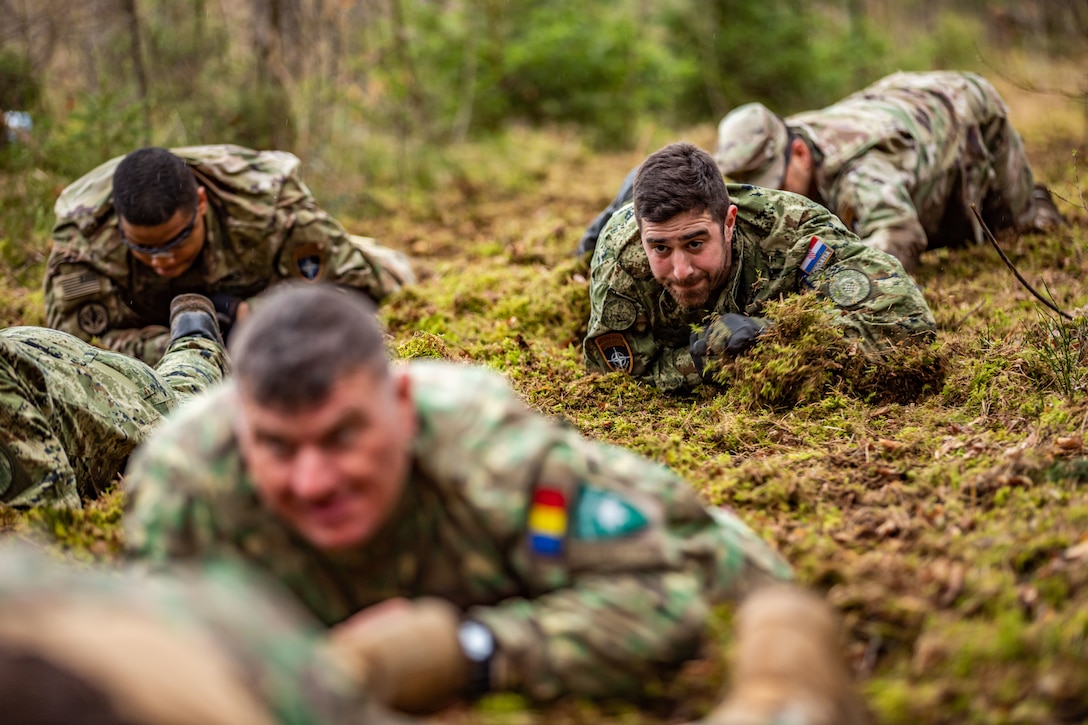 Soldiers crawl on the ground during a training exercise.
