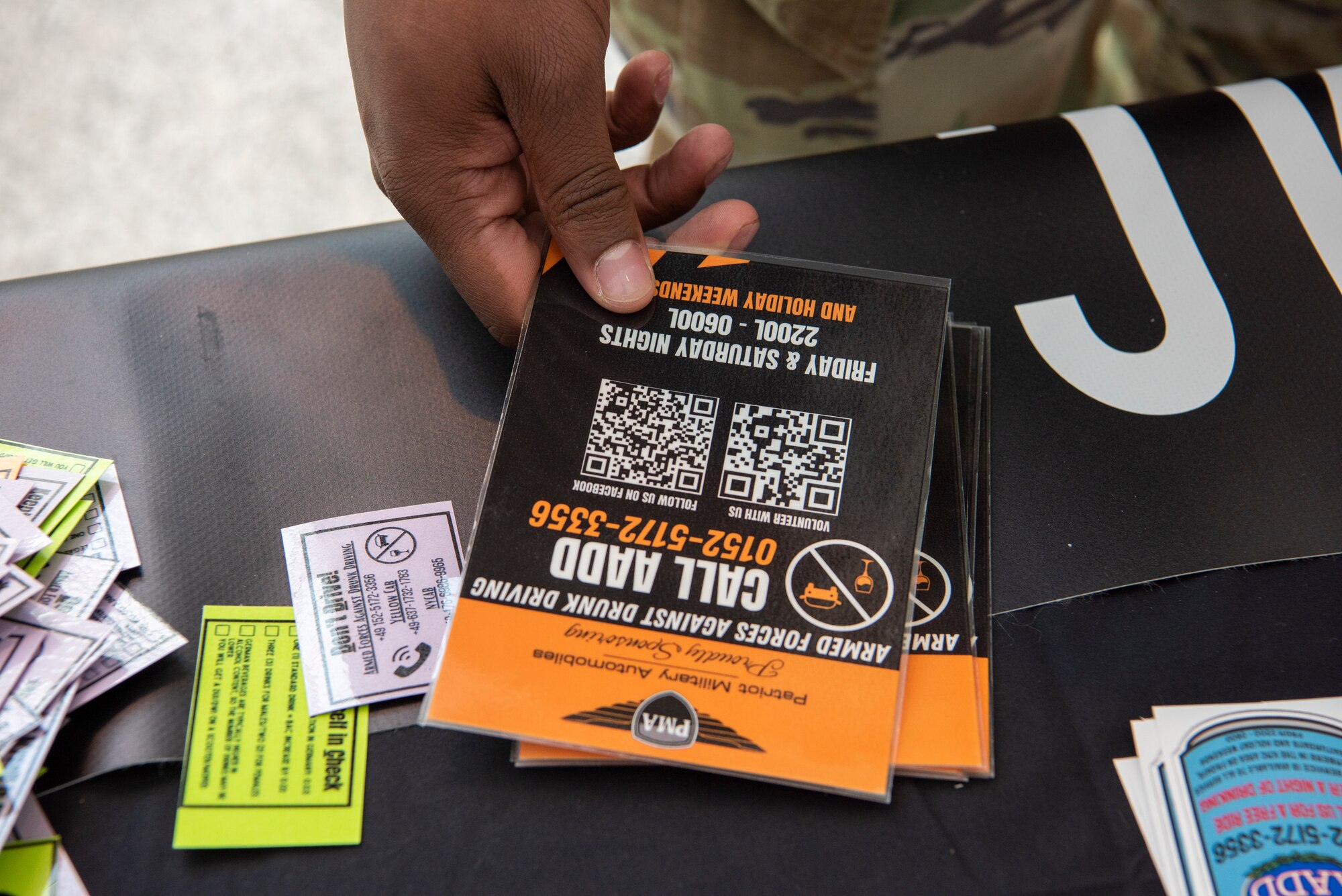 A service member takes an Armed Forces Against Drunk Driving card during an e-CheckUpToGo information fair at Ramstein Air Base, Germany, April 27, 2023.