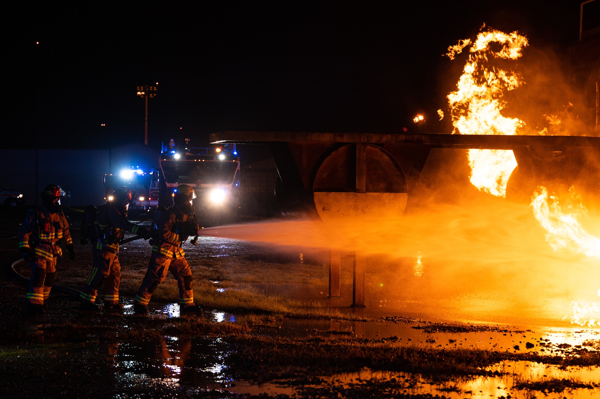 Firefighters assigned to the 100th Civil Engineer Squadron approach a controlled fire using a hand line during a base-wide exercise at Royal Air Force Mildenhall, England, April 28, 2023.
