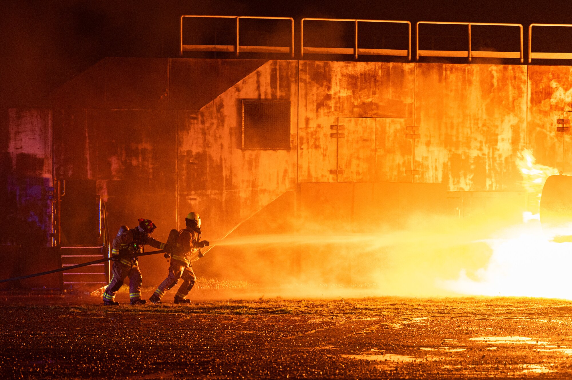 Firefighters assigned to the 100th Civil Engineering Squadron approach a controlled fire using hand lines during a base-wide exercise at Royal Air Force Mildenhall, England, April 27, 2023.