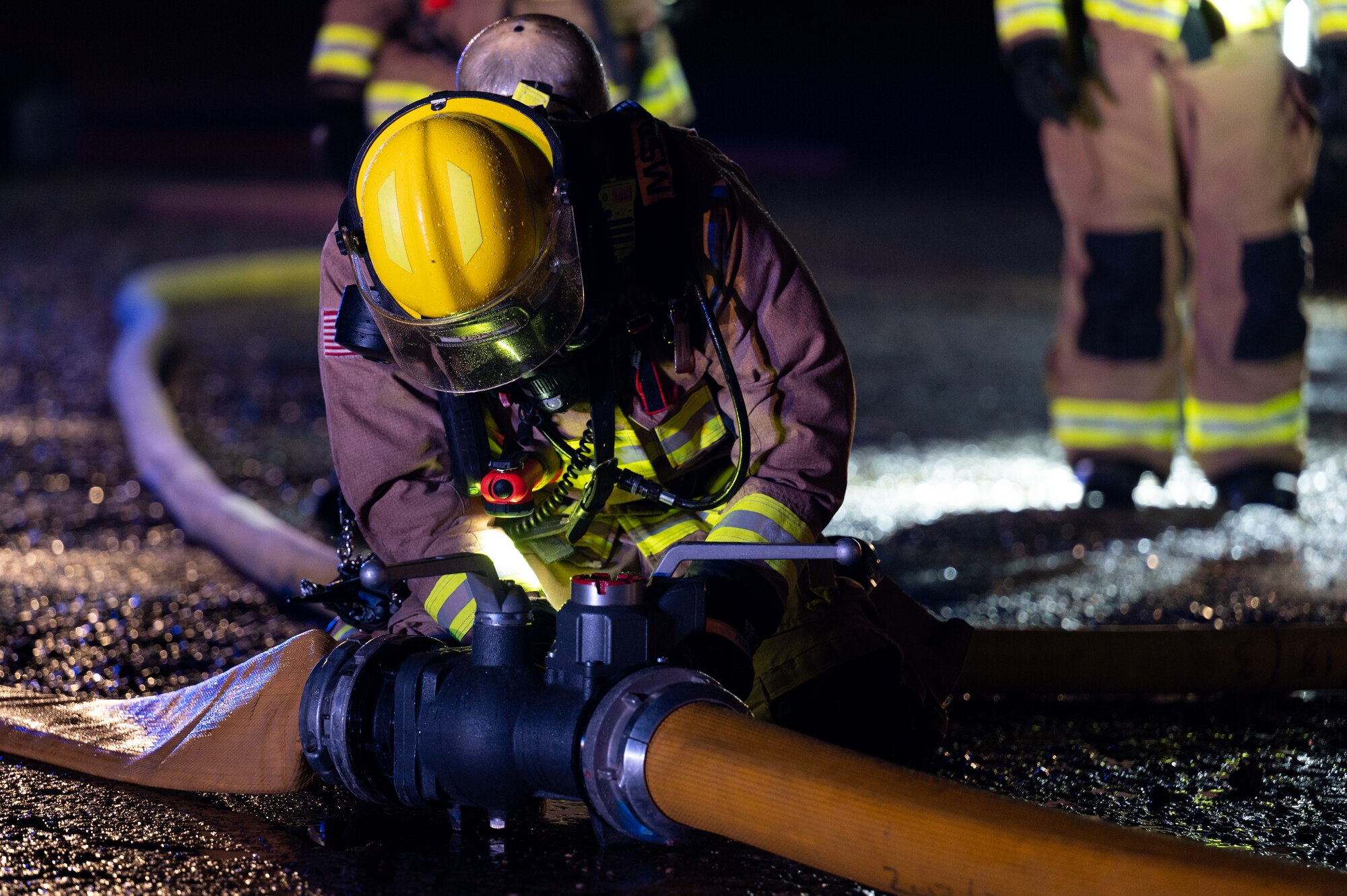 A 100th Civil Engineer Squadron firefighter, connects hoses to a manifold during a base-wide exercise at Royal Air Force Mildenhall, England, April 28, 2023.