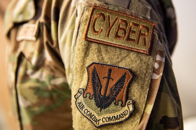Patches on the sleeve of a military uniform say “cyber” and “Air Combat Command.”