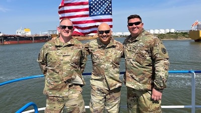 three men in military uniforms stand together on a boat