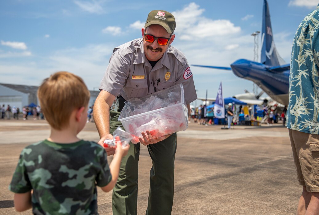 Zach Stafford, Park Ranger with the Galveston District, U.S. Army Corps of Engineers (USACE), hands out water safety whistles to visitors of the Hurricane Hunter Aircraft display at Ellington Airport.